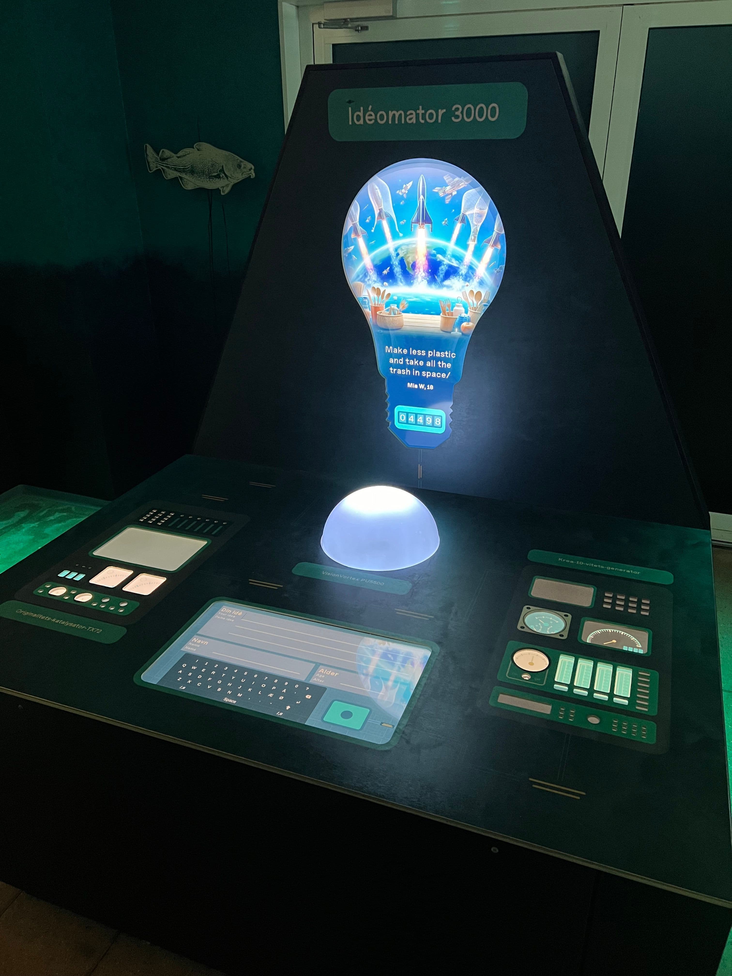 Photo of the Idea Machine enclosure in the Dødvande exhibition at Kattegatcentret, showing the four-display setup and DMX lighting