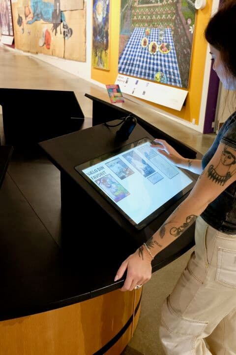 User exploring selected artworks at kiosk station after handheld data offload